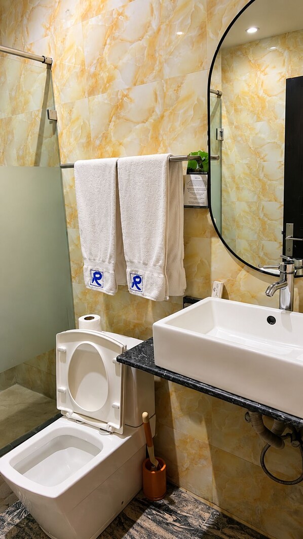 A bathroom with a toilet, bidet, sink, and a mirror.