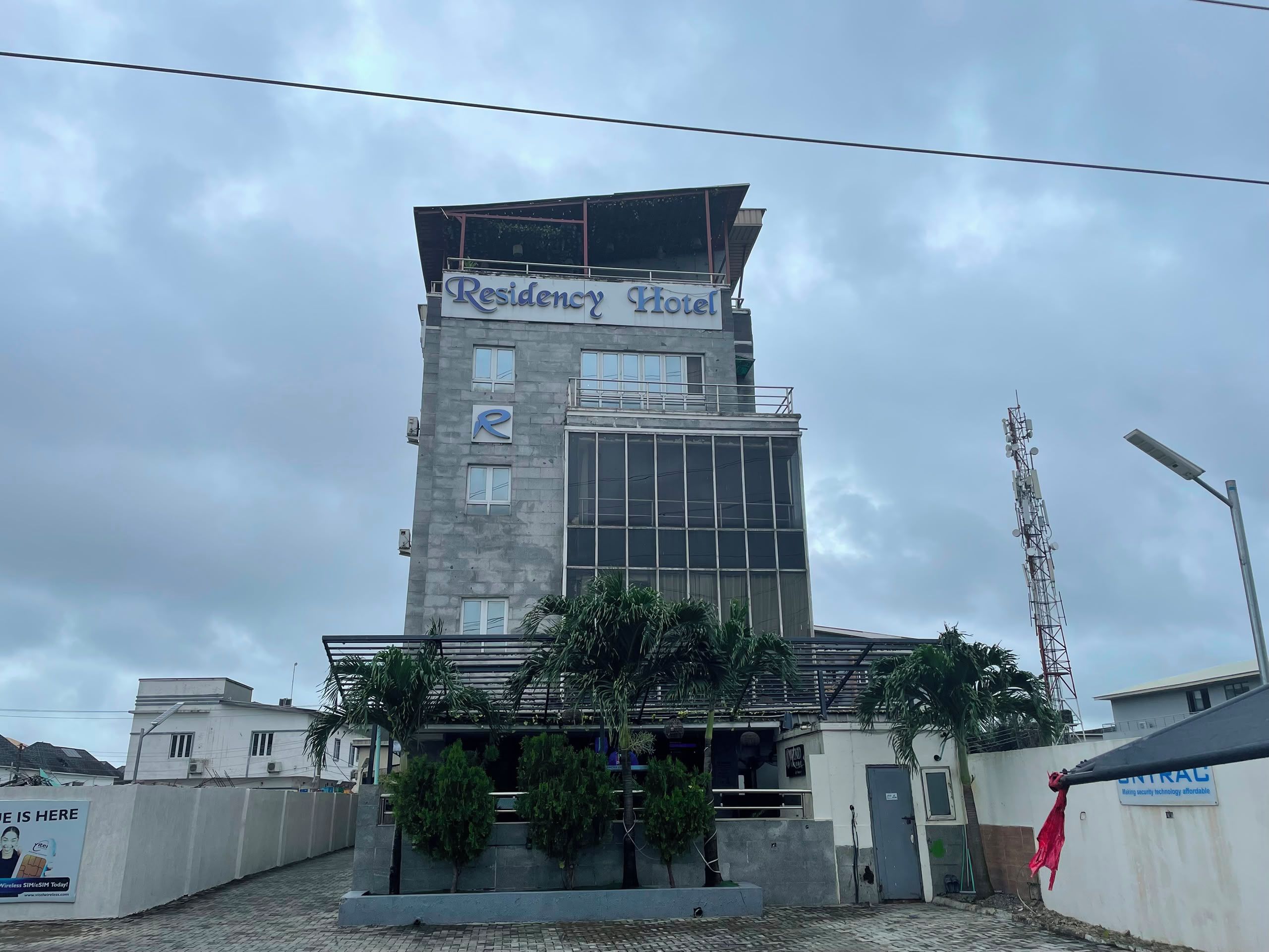 A multi-story building with a sign reading 'Residency Hotel' and a logo with an 'R'.