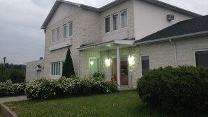 A two-story house with a stone facade, a covered front porch, and a well-maintained lawn. - Motel Econo-Nuit (Sherbrooke)