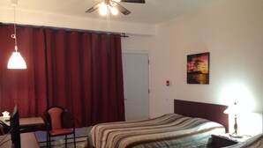 A hotel room with two beds, a desk, a chair, a ceiling fan, and a painting on the wall. - Motel Econo-Nuit (Sherbrooke)