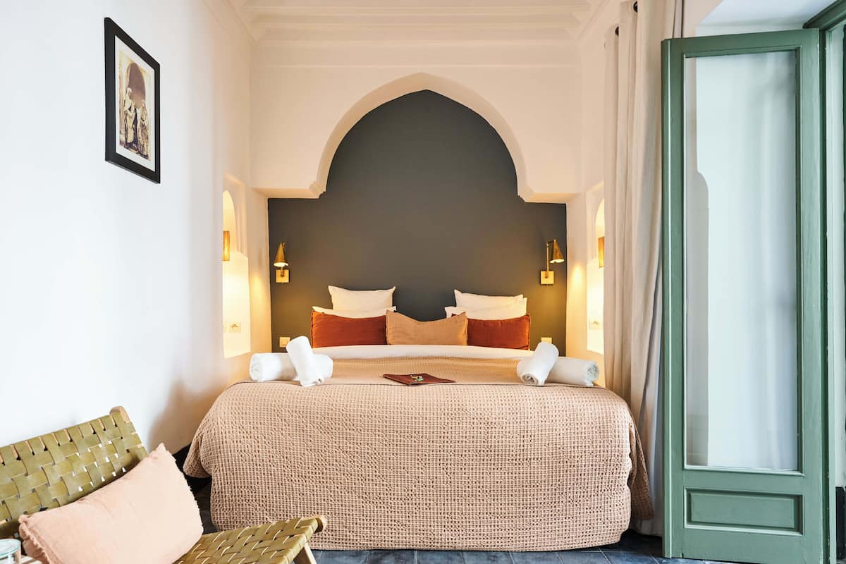 A hotel room with a large bed, a green door, and a framed picture on the wall.