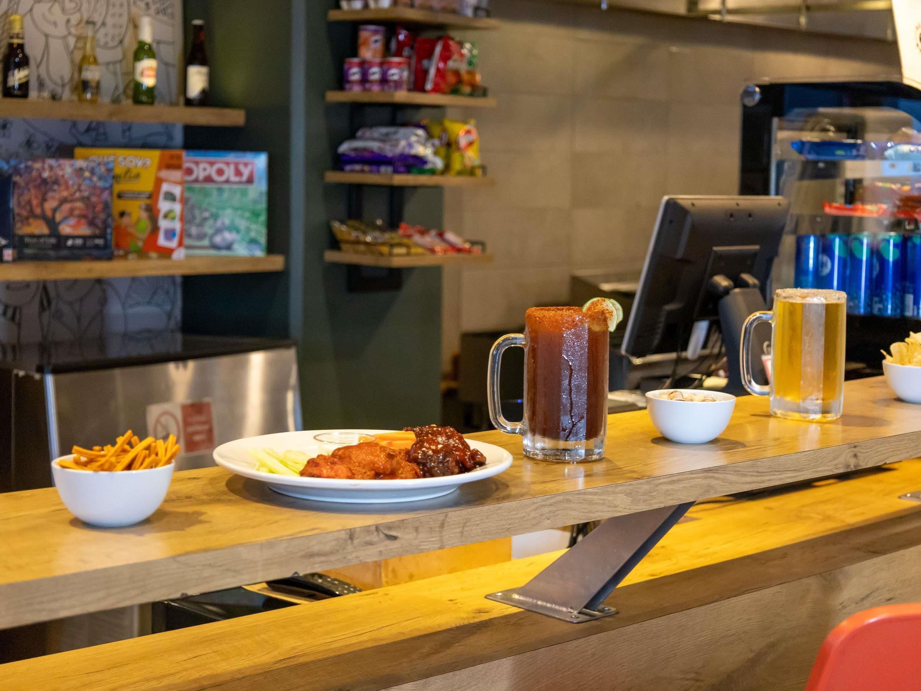Un espace bar avec un comptoir, un grand verre à bière, un verre de thé glacé et une assiette de nourriture.