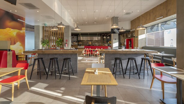 A modern restaurant with high ceilings, pendant lighting, and a central bar area. - ibis Queretaro (Querétaro)