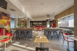 Un restaurante moderno con techos altos, iluminación colgante y una zona de bar central.