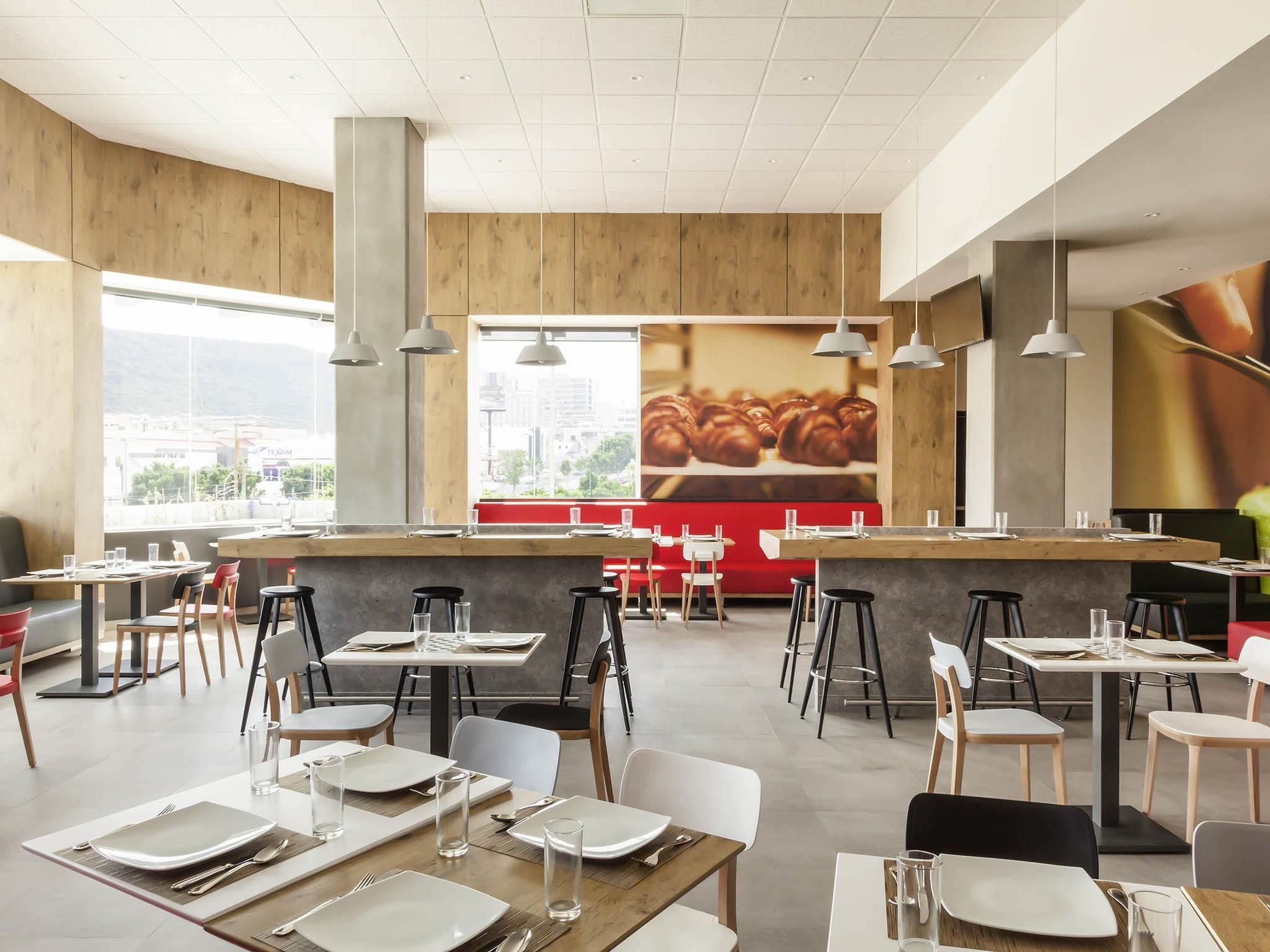 Un restaurante moderno con una barra central, varias mesas y sillas.
