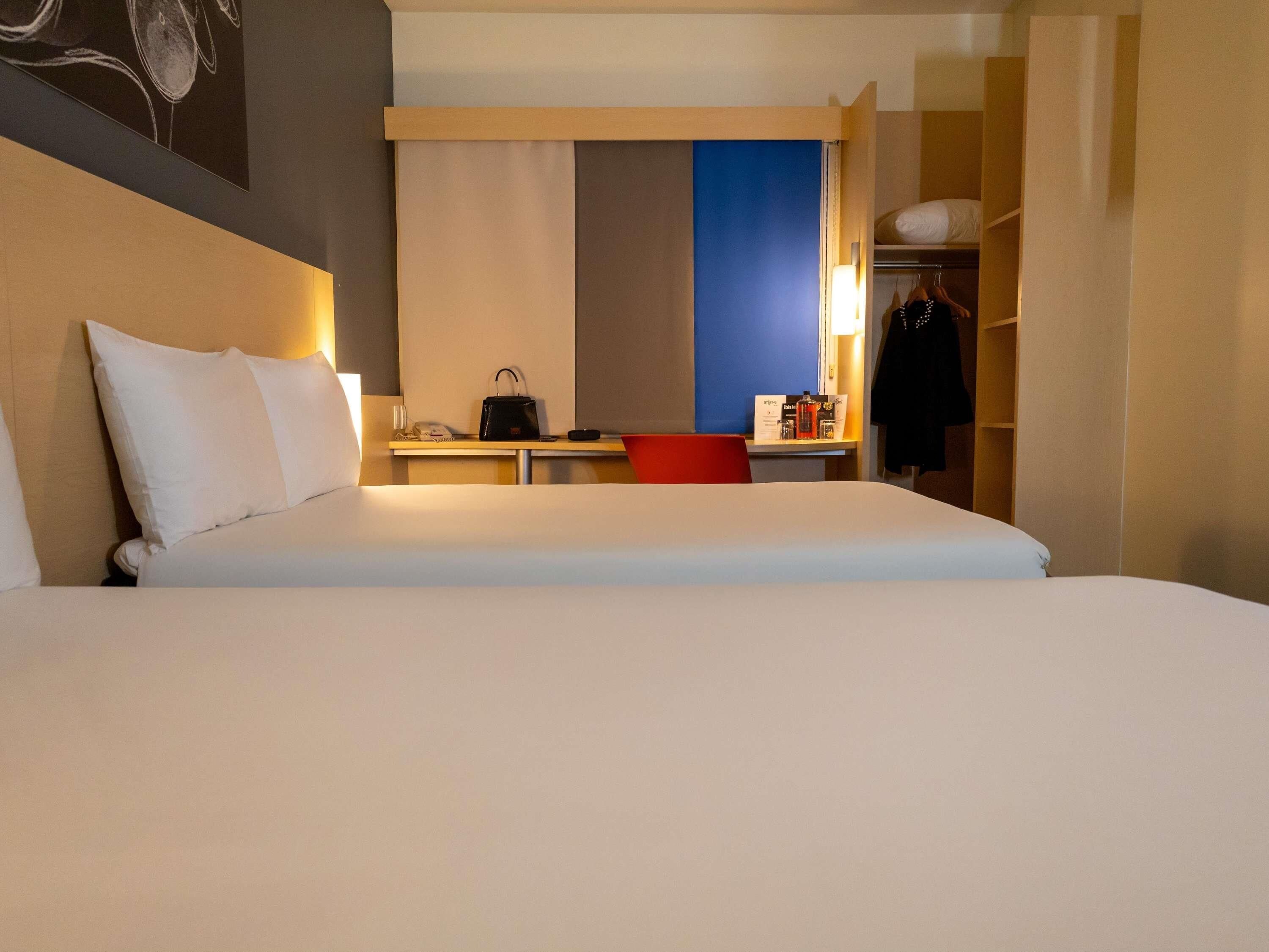 Una habitación de hotel con una cama grande, un escritorio con una silla, un armario y un espejo.