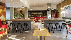 A modern restaurant interior with a central bar, high ceiling, and natural lighting. - ibis Queretaro (Querétaro)