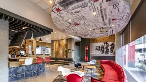 A modern interior with a curved ceiling, seating areas, and a visible kitchen area. - ibis Queretaro (Querétaro)