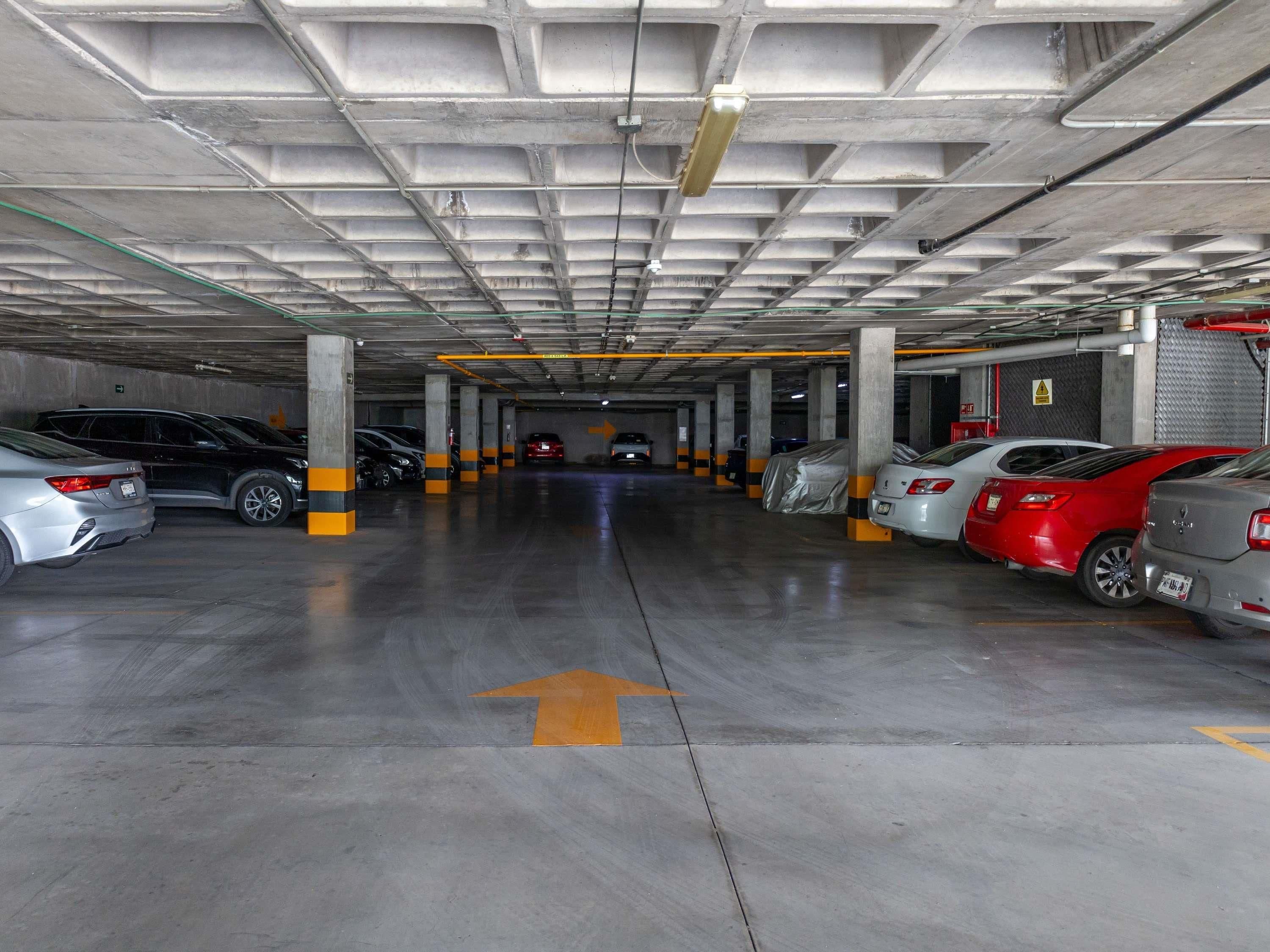 A multi-level underground parking garage with cars parked on multiple levels and directional arrows on the floor.