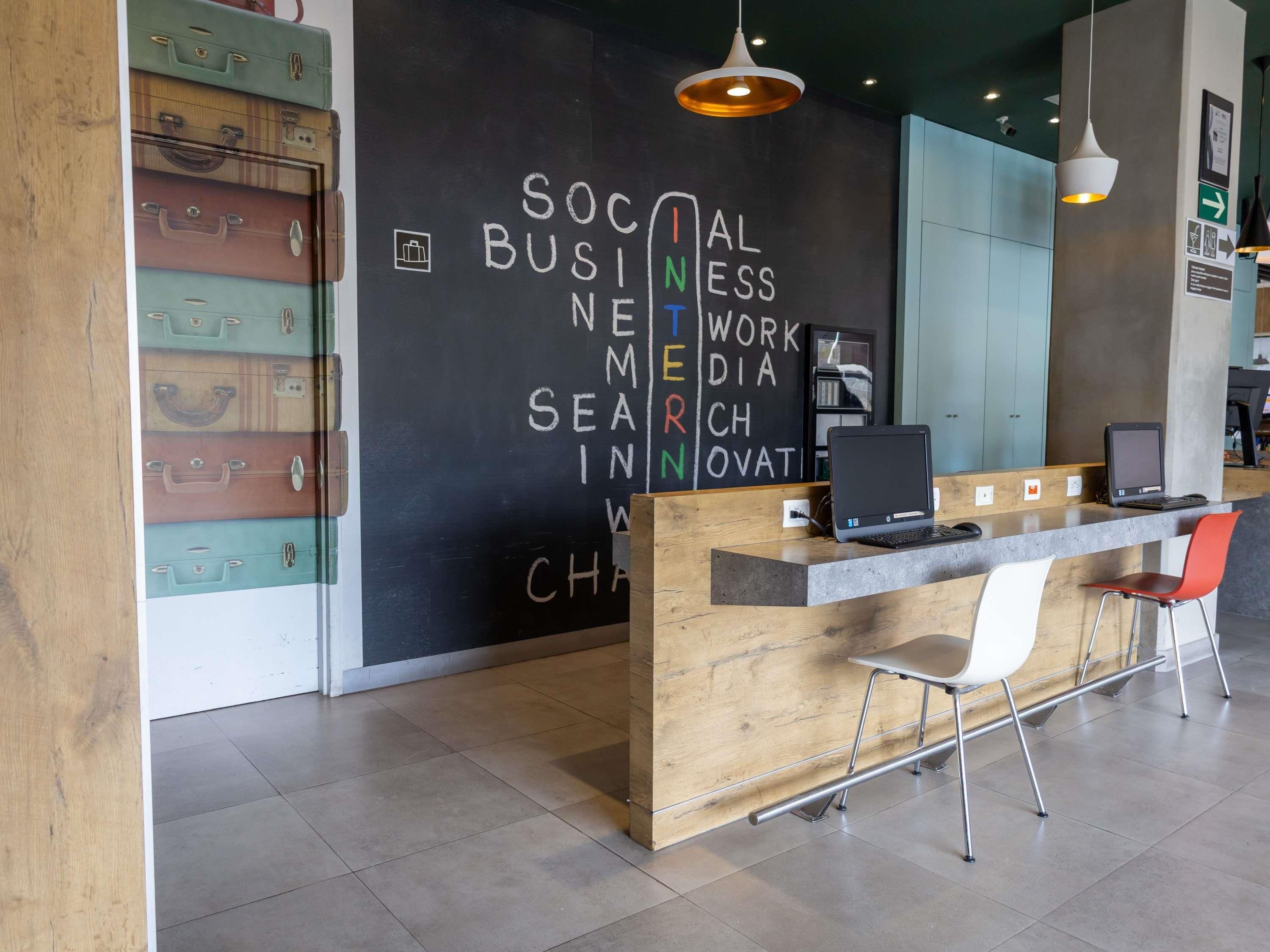 A reception desk with a laptop, a wooden counter, and a modern chair.