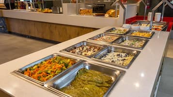 Un bufé con diversas opciones de comida, incluyendo ensaladas, carnes y otros platos.