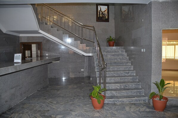 Un escalier en marbre avec des rampes en métal, des plantes en pot et un tableau encadré au mur.