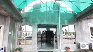 A building entrance with a glass door, potted plants, and air conditioning units. - Residency Hotel Leophine House (Ogbunike)
