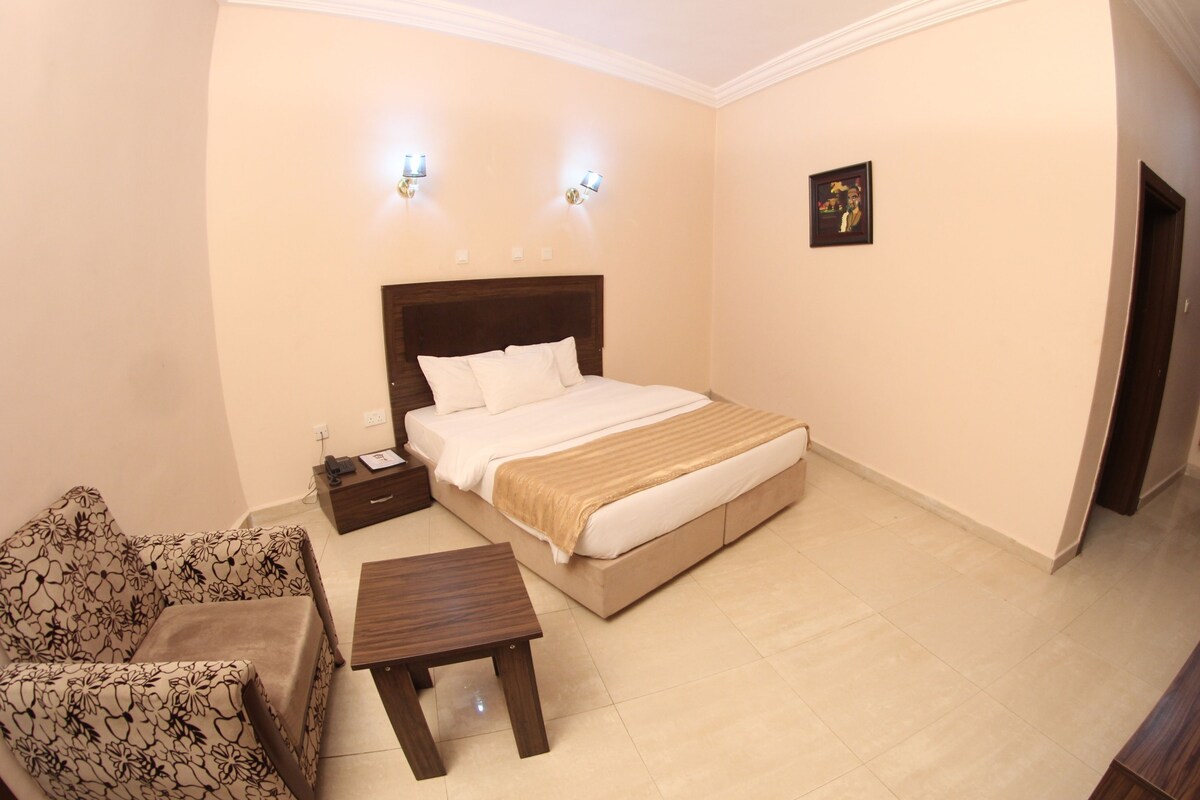 Une chambre d’hôtel comprenant un lit, une table de chevet, une chaise et une petite table.