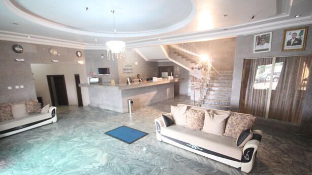 A spacious lobby with a reception desk, a staircase, and a sofa area. - Residency Hotel Leophine House (Ogbunike)