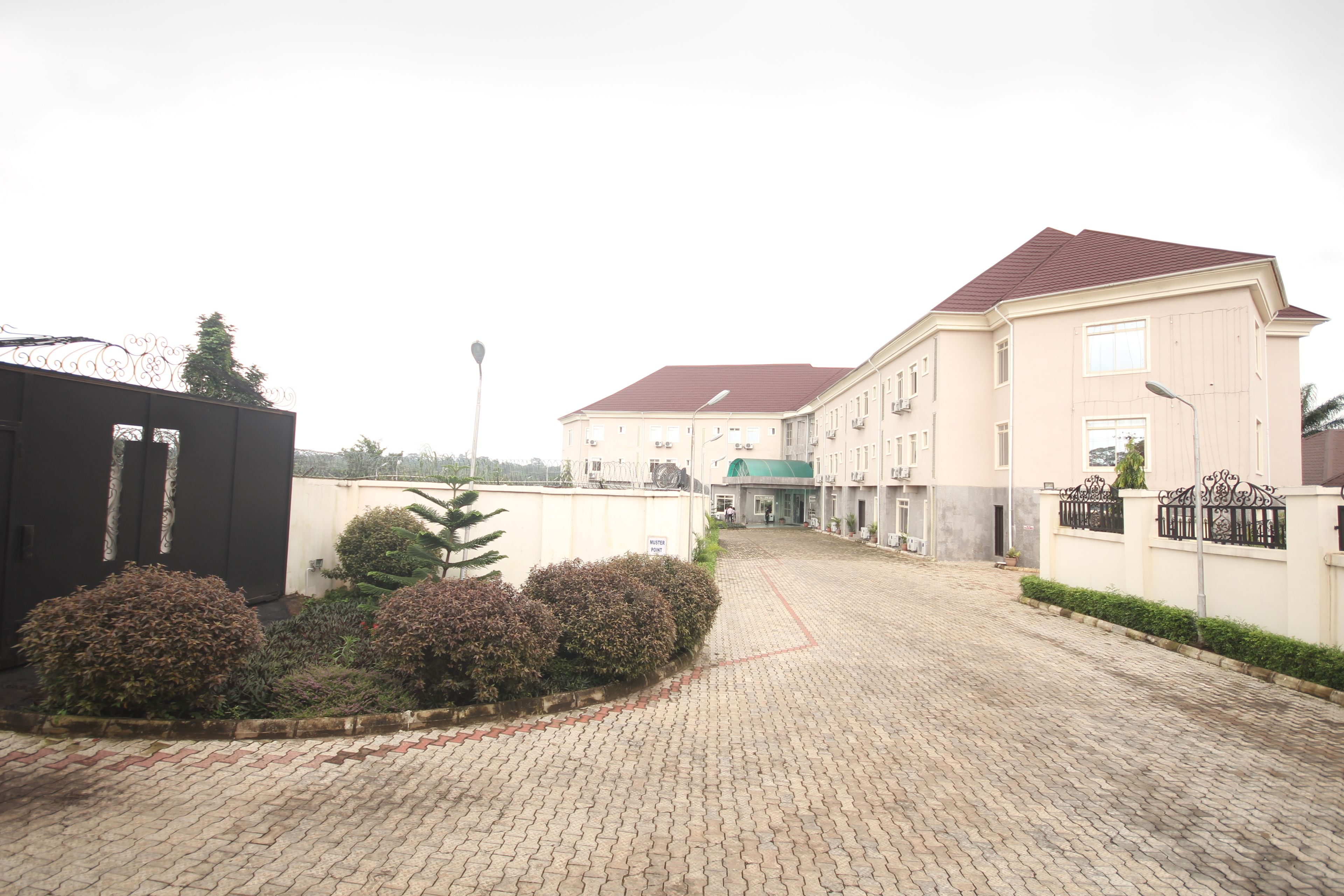 A paved driveway leading to a building with a red roof and beige walls.