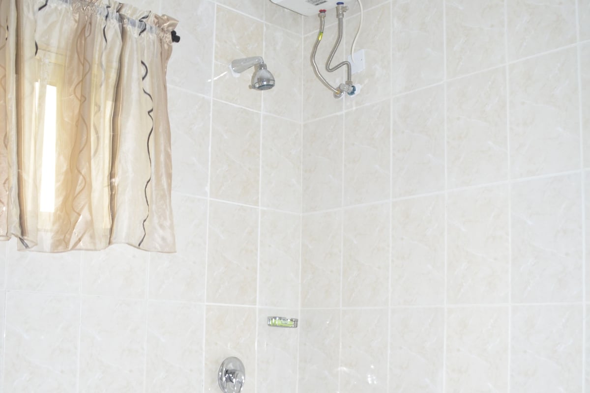 Une salle de bain dotée d’une grande baignoire, d’une douche et d’un chauffe-eau fixé au mur.