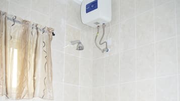 Un baño con una bañera grande, un cabezal de ducha y un calentador de agua instalado en la pared.