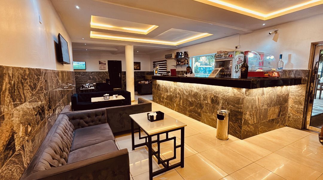 Un vestíbul modern amb taulell de recepció de marbre, zona de seients i bar.