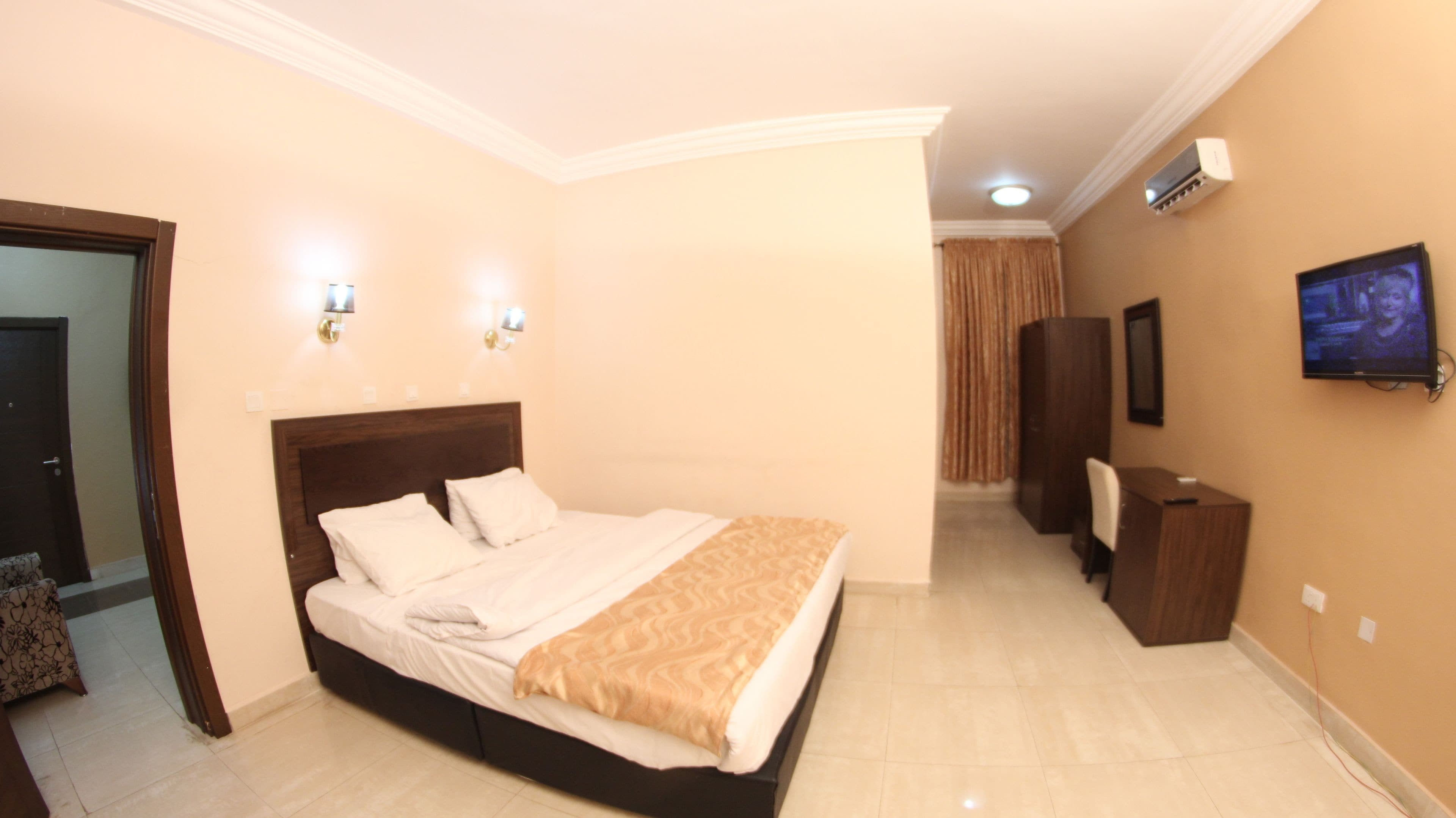 Une chambre d’hôtel équipée d’un grand lit, d’un bureau, d’une chaise, d’une télévision et d’un appareil de climatisation.