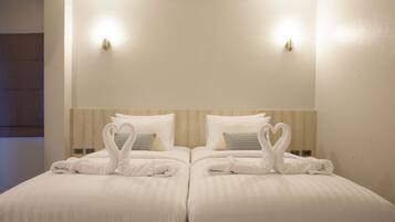 A hotel room with two beds, each with a heart-shaped towel arrangement.