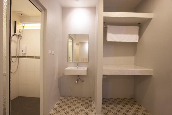 A small, clean bathroom with a white sink, a mirror, and a towel hanging on a rack.
