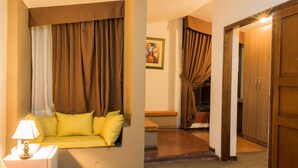 Quarto de hotel com sofá, luminária e pintura na parede.