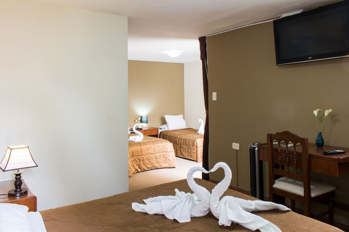 Ein Hotelzimmer mit Bett, Schreibtisch, Stuhl, Fernseher und Lampe.