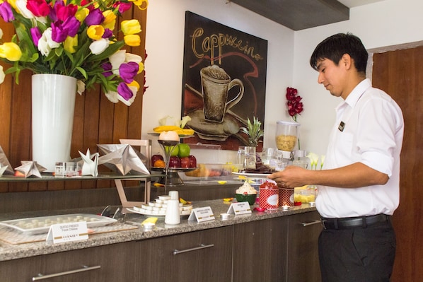 A breakfast bar with a variety of food items and a coffee-themed wall art.