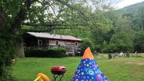 A grassy area with a tent, a grill, and outdoor furniture. - Cold Spring Lodge (Big Indian)