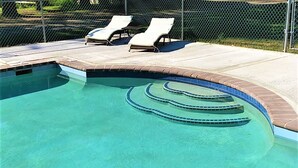 A swimming pool with clear blue water, a brick border, and two lounge chairs. - Cold Spring Lodge (Big Indian)