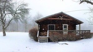 A log cabin with a porch and steps leading up to the door. - Cold Spring Lodge (Big Indian)