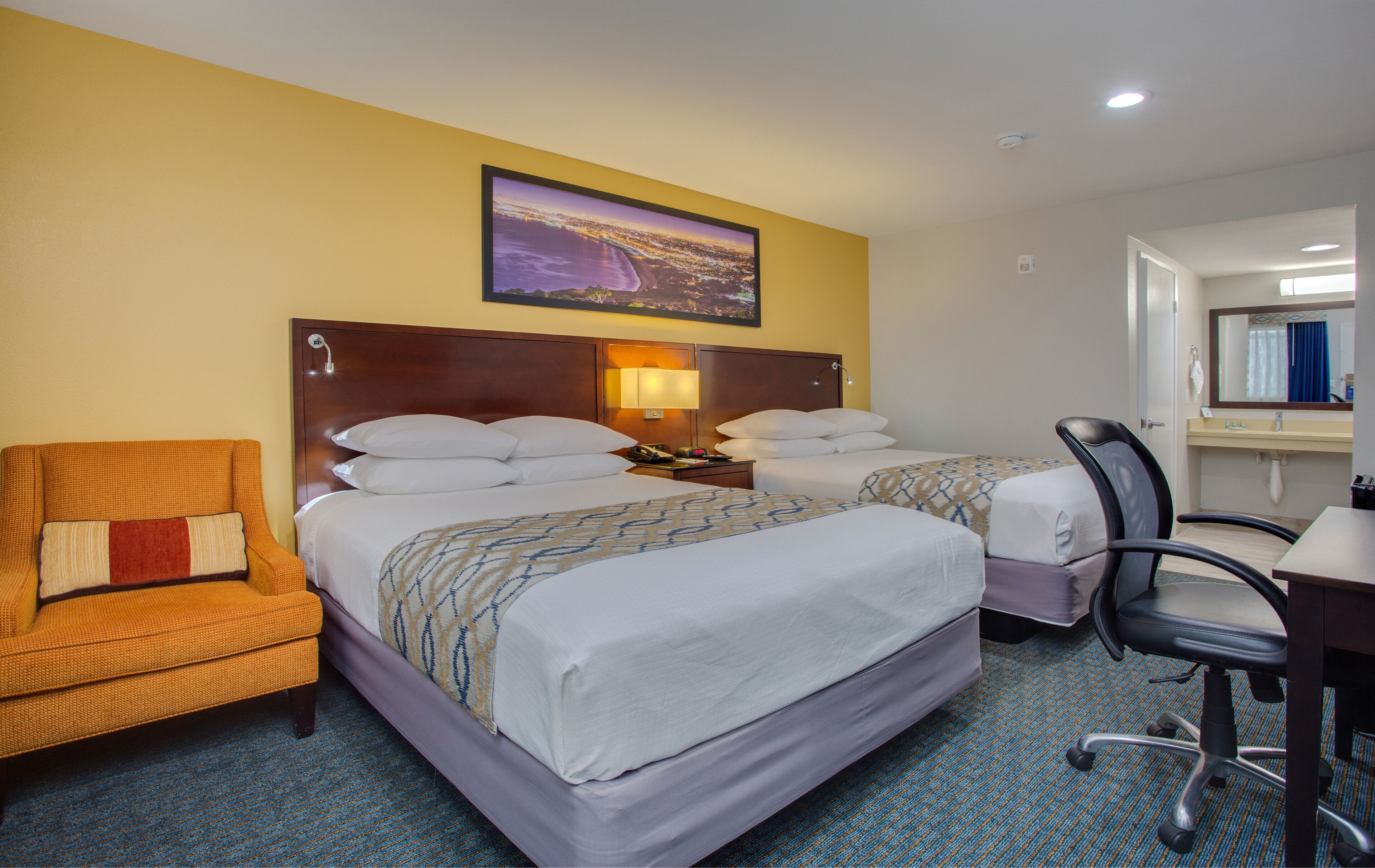 Une chambre d’hôtel avec deux lits, une chaise, un bureau et une salle de bain.