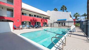 Una piscina al aire libre, sillones reclinables de piscina