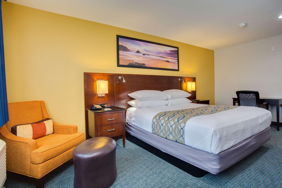 Ein Hotelzimmer mit Bett, Stuhl, Schreibtisch und Nachttisch.