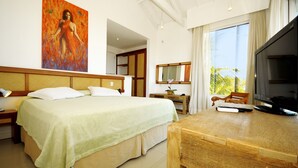 A hotel room with a bed, a wooden desk, a television, and a painting on the wall. - Pousada Pelicano (Búzios)