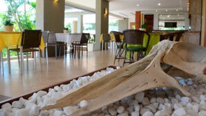 A dining area with a large bone centerpiece, tables, chairs, and a view of the kitchen in the background. - Pousada Pelicano (Búzios)