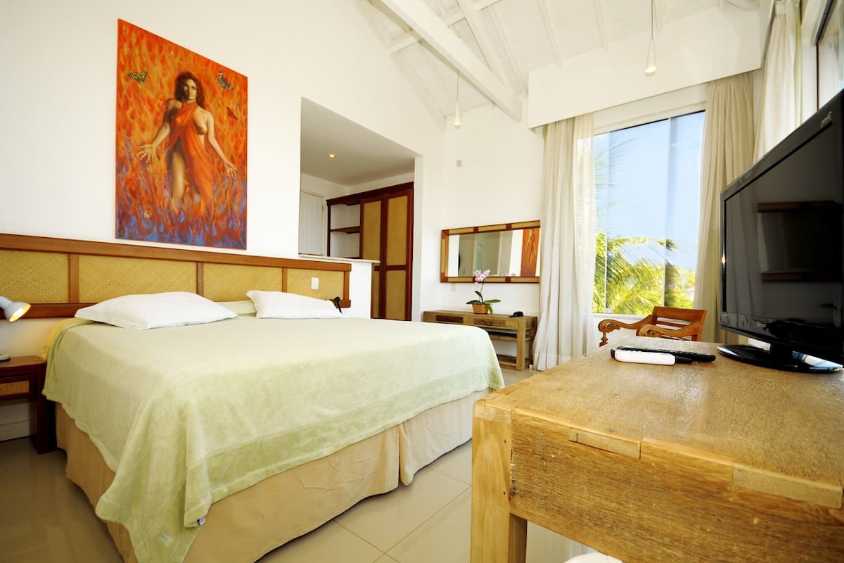 Una habitación de hotel con cama, escritorio, televisor y un cuadro en la pared.