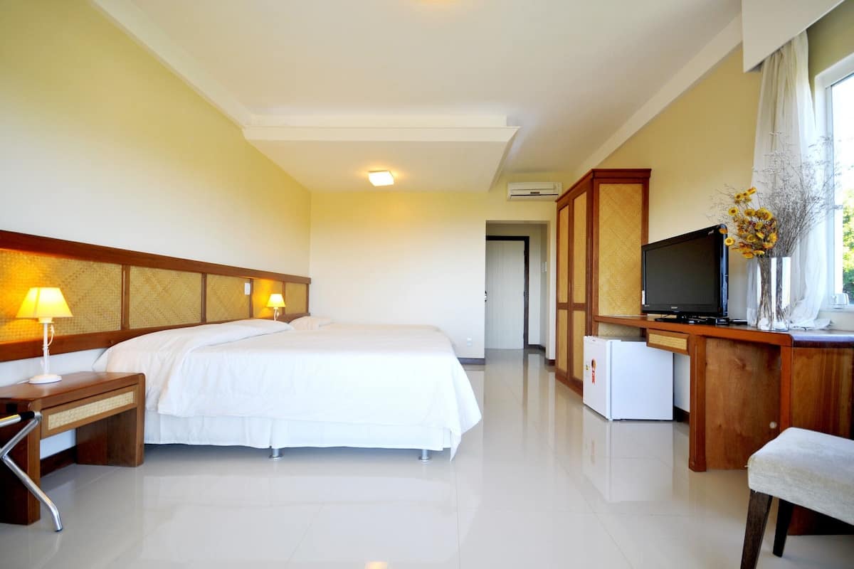 Una habitación de hotel con cama, escritorio, televisión y un refrigerador pequeño.