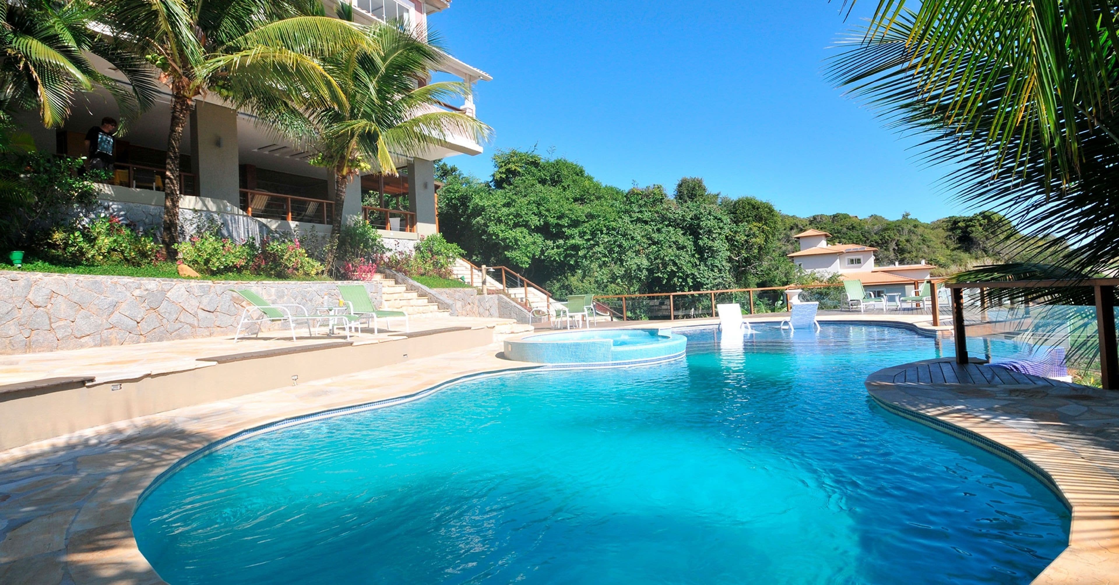 Una piscina al aire libre, sombrillas, sillones reclinables de piscina