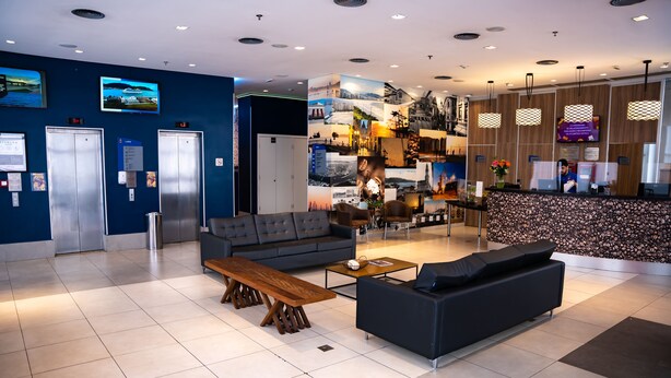 A modern lobby with a reception desk, seating area, and elevators. - Comfort Hotel Santos (Santos)