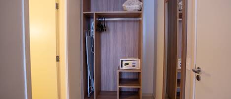 A walk-in closet with wooden shelving, a hanging rack, and a microwave on the lower shelf.