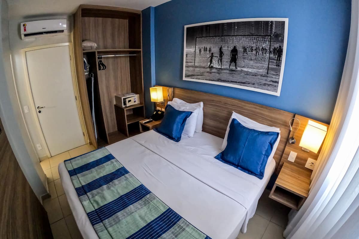 A hotel room with a bed, a nightstand, a bedside lamp, a wardrobe, and a wall-mounted picture.