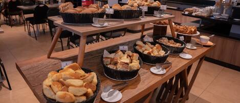 A buffet table with various bread and pastries.