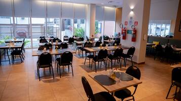 A spacious restaurant with multiple tables and chairs, large windows, and a fire extinguisher on the wall.