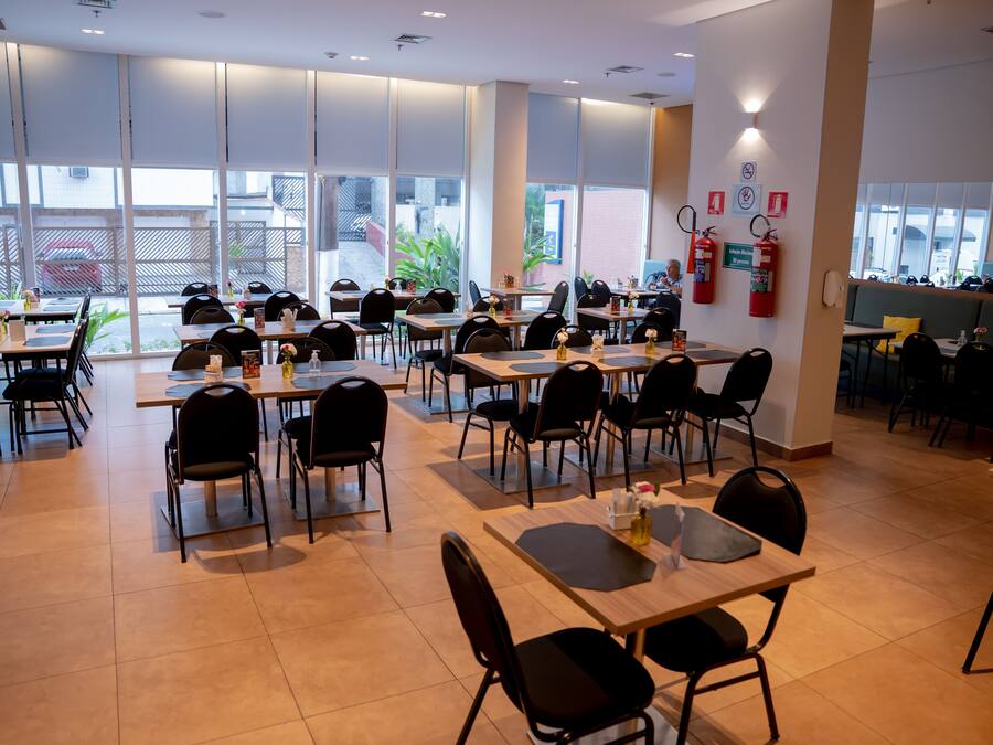 A spacious restaurant with multiple tables and chairs, large windows, and a fire extinguisher on the wall.