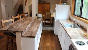 Una cocina con encimera de mármol, armarios de madera, un fregadero y una estufa.