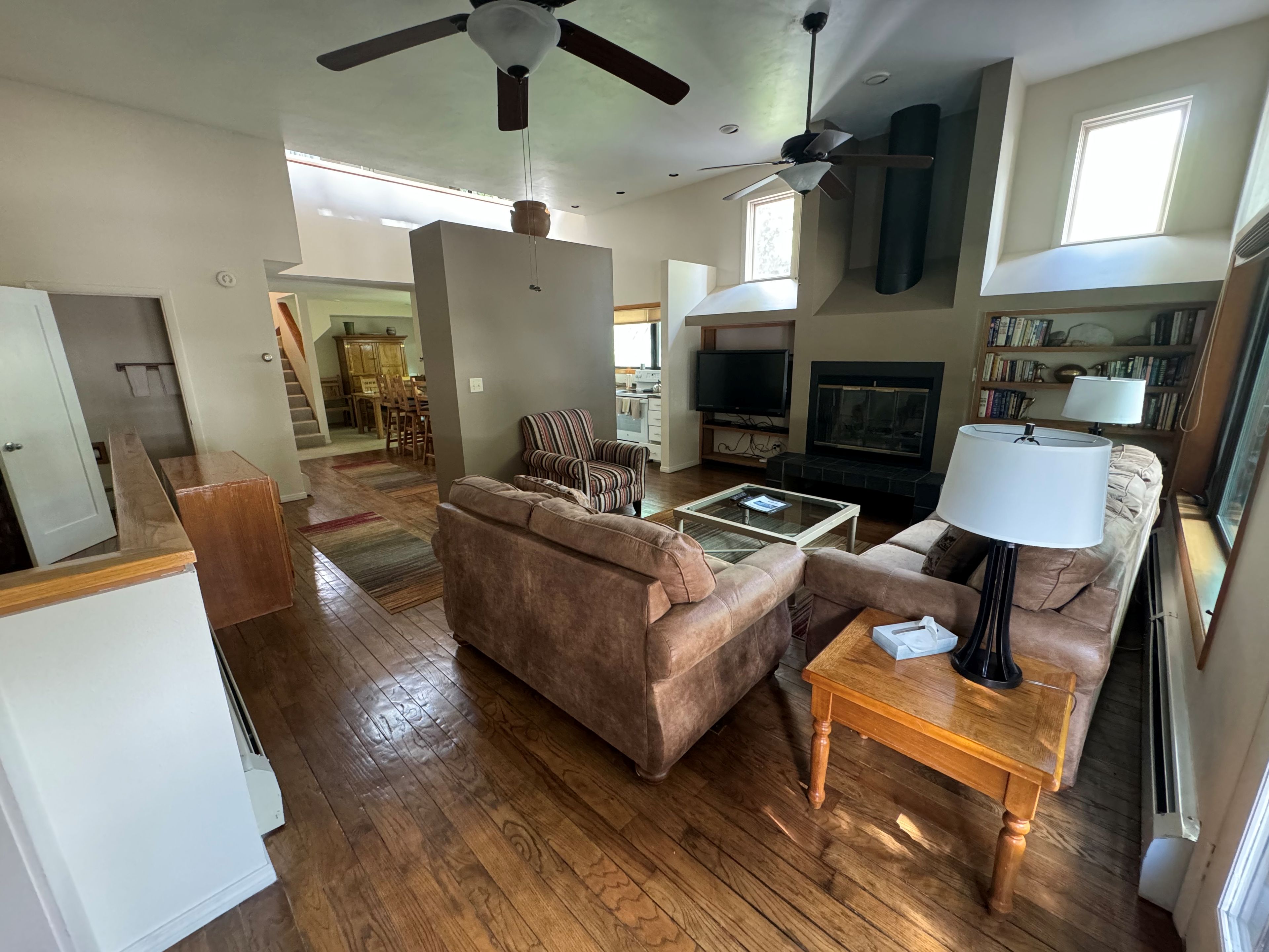A spacious living room with a brown sofa, a coffee table, a television, and a fireplace.