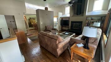 A spacious living room with a brown sofa, a coffee table, a television, and a fireplace.