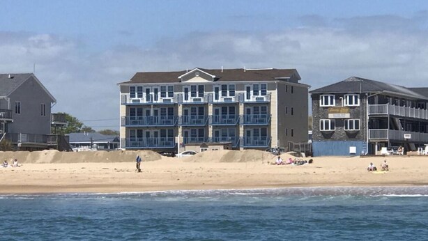 A beachfront hotel with multiple floors, balconies, and a sandy beach in the background. - Misquamicut Beach Front Inn (Westerly)